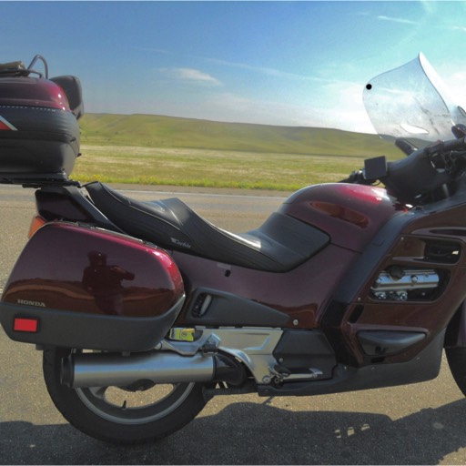 Side view of red Honda ST 1100 with hill of North Dakota gently rising in the background. 