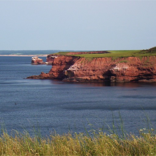 Photo of the red cliffs of PEI up against the ocean at the Gulf of St. Lawrence. 