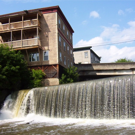 Apartment building on the left, beside a small waterfall, which may be the remnants of an old mill site. 