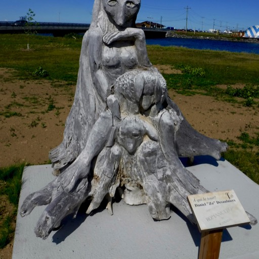 Sculpture of a female fox in the background, with smaller foxes in a pile in front of her. 
