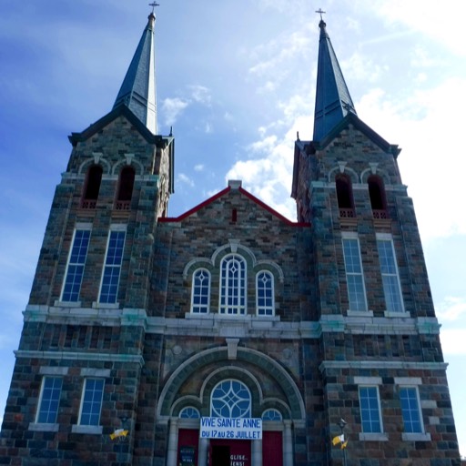 Photo of the front of a large, brick church with two towers in front. 