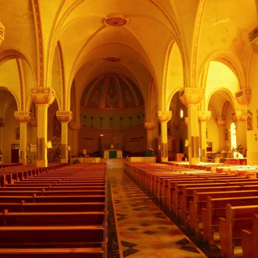 Interior of a large, Roman Catholic church, bathed in natural light. 