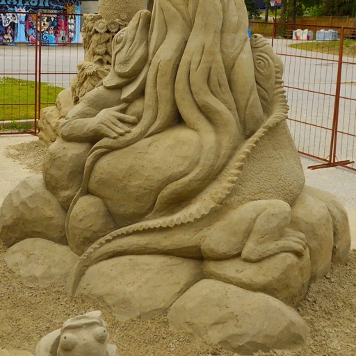 Sand sculpture of the lizard stalking its prey, which is a sleeping bird at the top of a tree. 