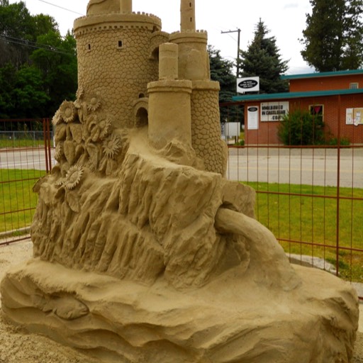 Sand sculpture of a sand castle with a stream coming from its back. 