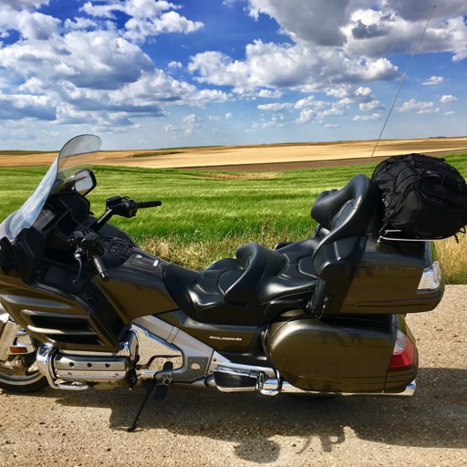 Side view of large Gold Wing motorcycle in the foreground, with the rolling prairie stretching into the distance. 