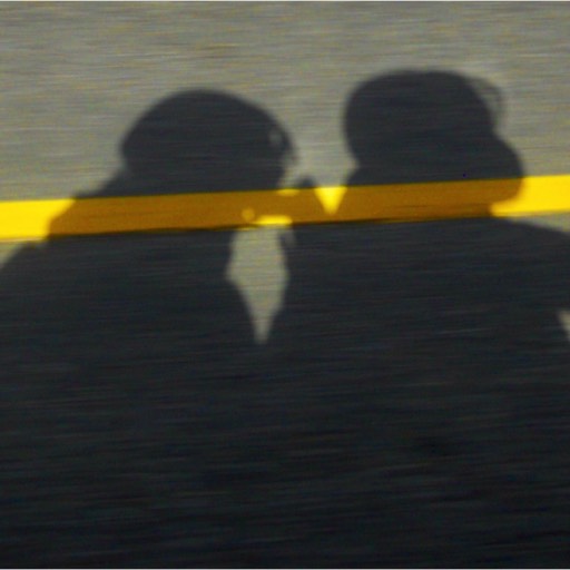 Photo of the shadow of Eric and Julie riding the Gold Wing east on the ashphalt highway. 