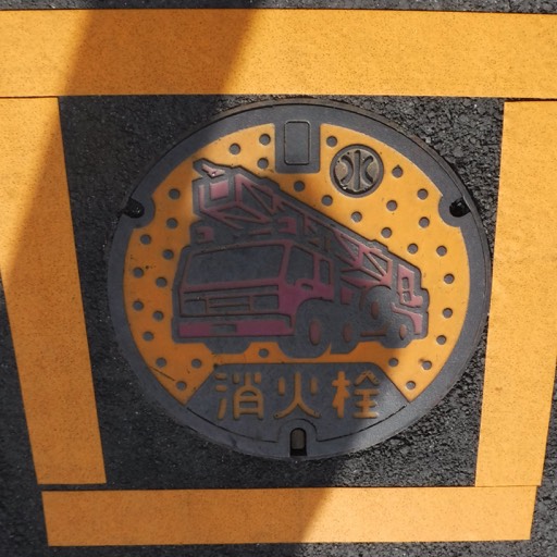 A stylized storm sewer cover with a yellow background and a stylized fire truck featured. 