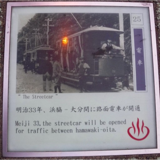 Photo on a sidewalk block showing a streetcar from the early 20th century. The inscription says that in Meiji 33 (about 1901), a streetcar line opened between Hamanwaki and Oita. 