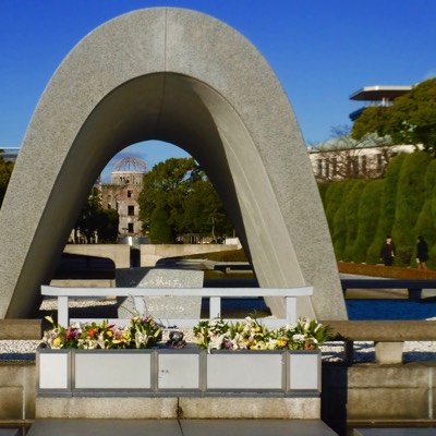 The memorial cenotaph covers a monument holding the names of everyone killed by the bomb. It is aligned to frame the Peace Flame and the A-Bomb Dome, and the arch shape represents a shelter for the souls of the victims. Translated to English, the epitaph contains a wish: 